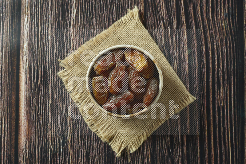 Dates in different bowls (wooden, pottery and glass) on wooden background