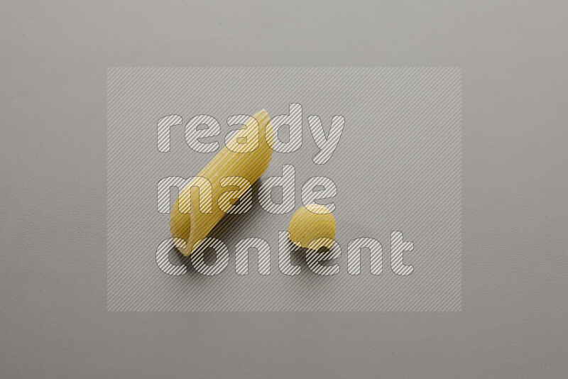 Penne pasta with other types of pasta on grey background