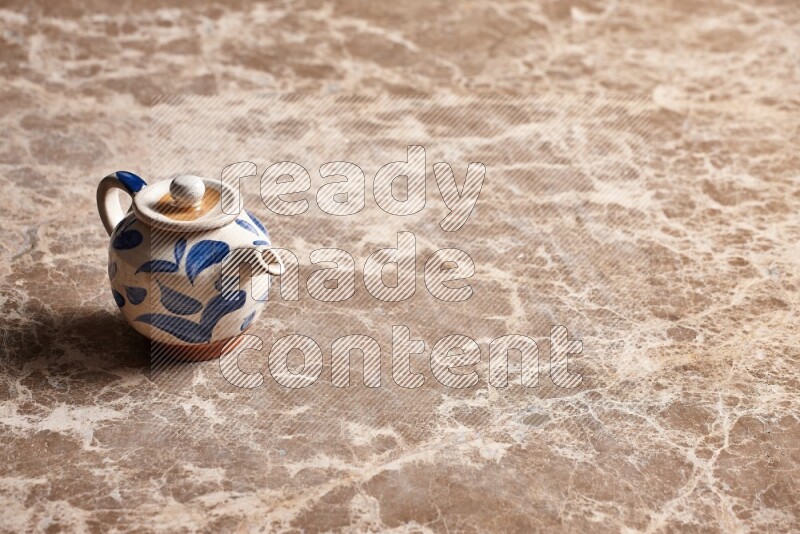 A pottery teapot on beige marble background