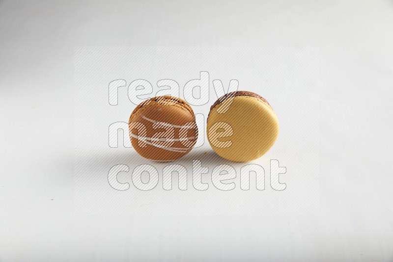 45º Shot of of two assorted Brown Irish Cream, and Yellow, and Brown Chai Latte macarons on white background