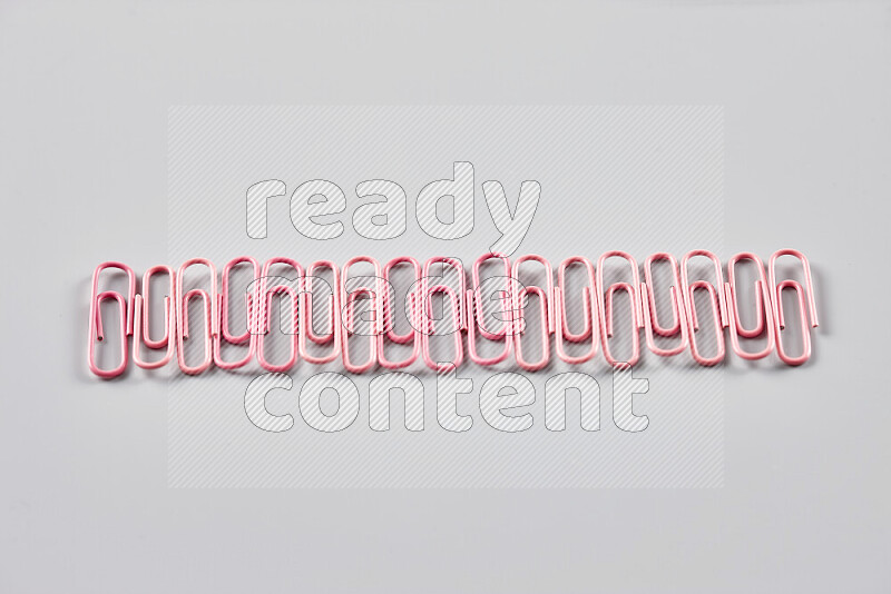 Pink paper clips isolated on a grey background
