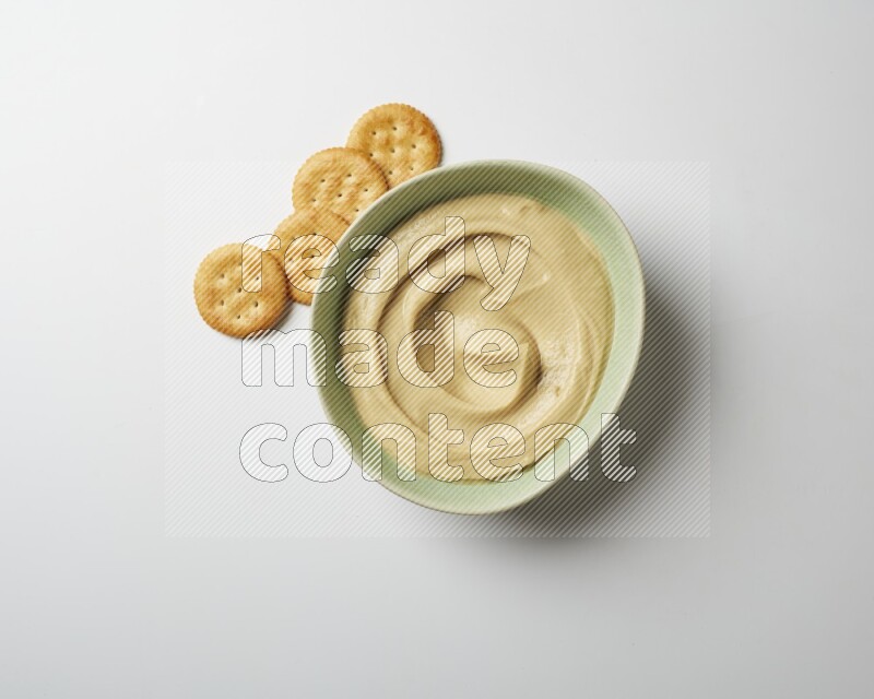 plain Hummus in a green plate on a white background