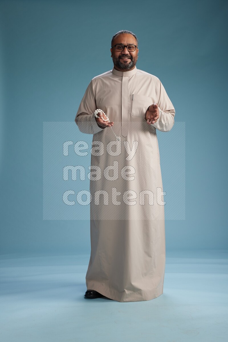 Saudi Man without shimag Standing Interacting with the camera on blue background