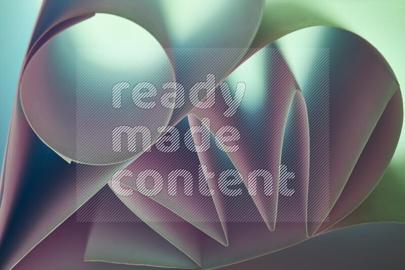 An artistic display of paper folds creating a harmonious blend of geometric shapes, highlighted by soft lighting in green and pink tones