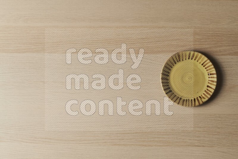 صحن فخاري متعدد الألوان على خلفية خشبية فاتحة