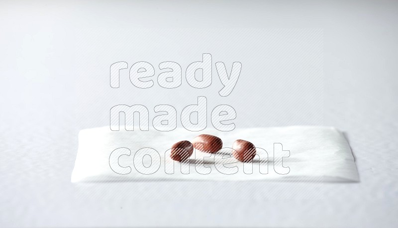 3 red skin peanuts on a piece of paper on a white background in different angles