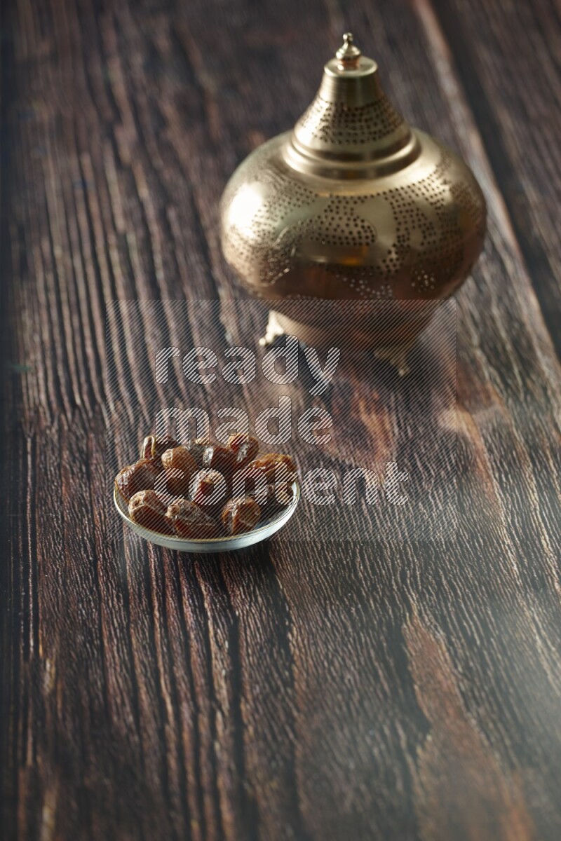 A golden lantern with different drinks, dates, nuts, prayer beads and quran on brown wooden background