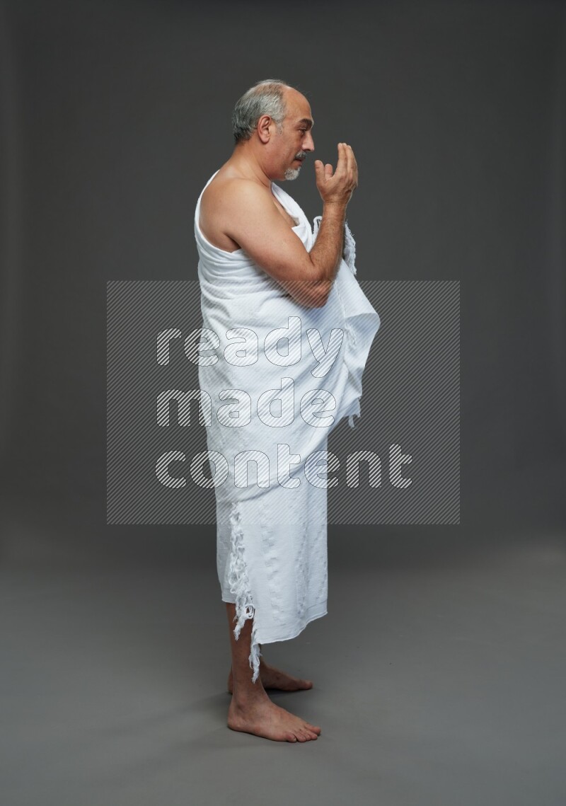 A man wearing Ehram Standing dua'a on gray background