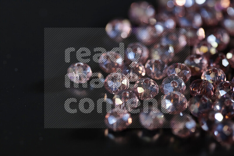Rose transparent crystal beads scattered on a black background