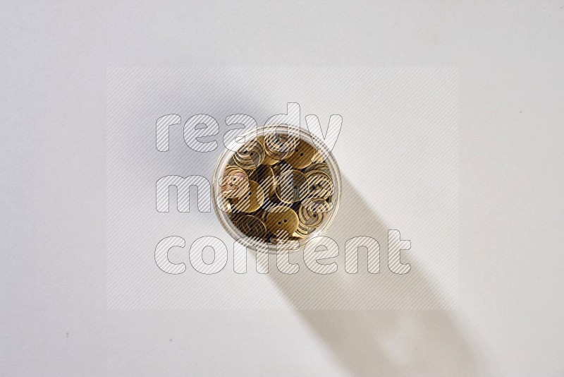 A glass jar full of colored buttons on grey background