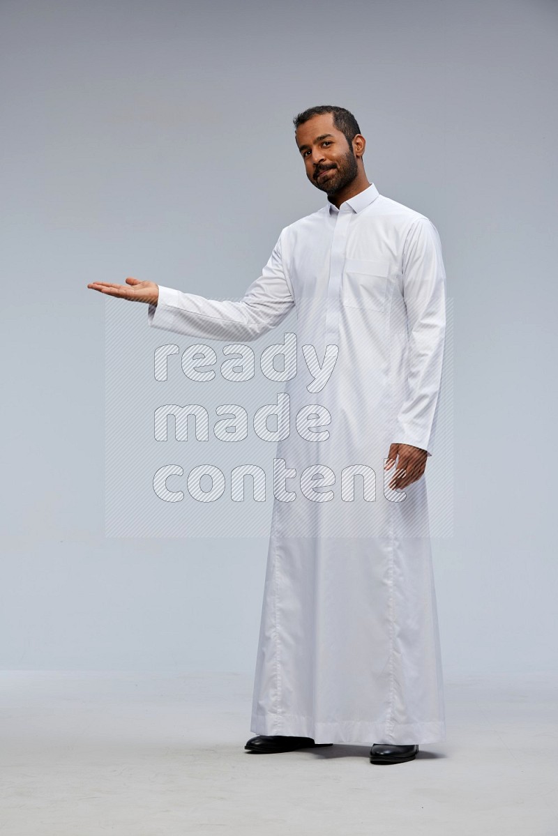 Saudi man Wearing Thob standing interacting with the camera on Gray background