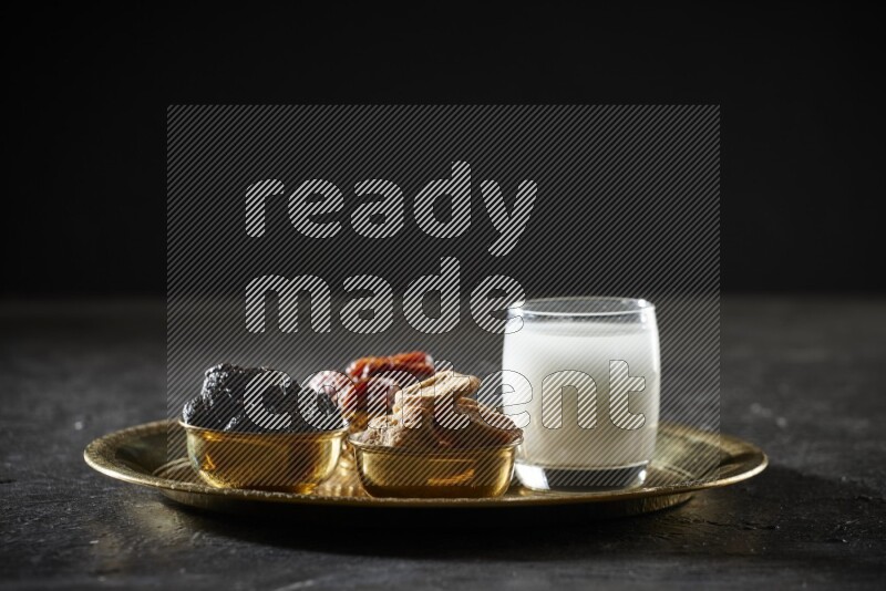 Dried fruits in metal bowls with sobya on a tray in dark setup