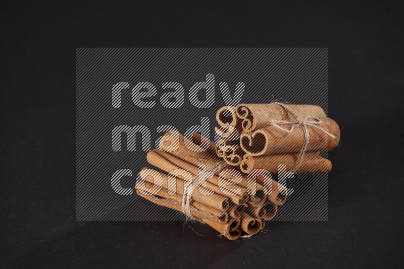 Two bounded stacks of cinnamon sticks on black background