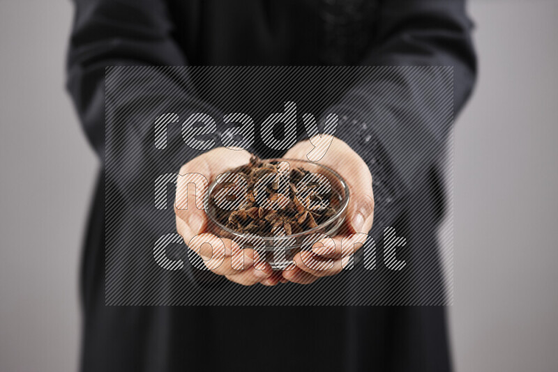 Woman in abaya holding different kinds of spices in different positions