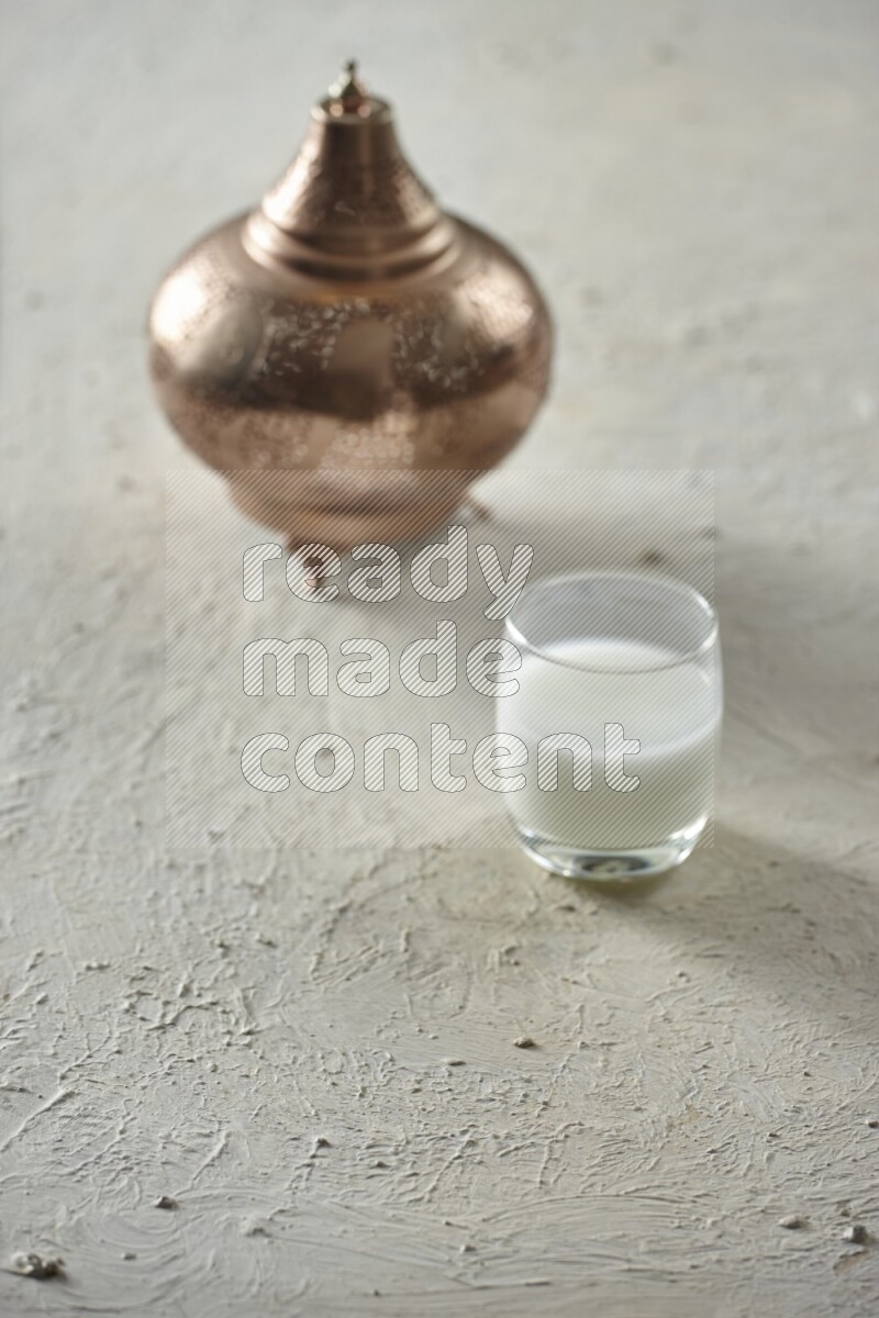 A golden lantern with different drinks, dates, nuts, prayer beads and quran on textured white background