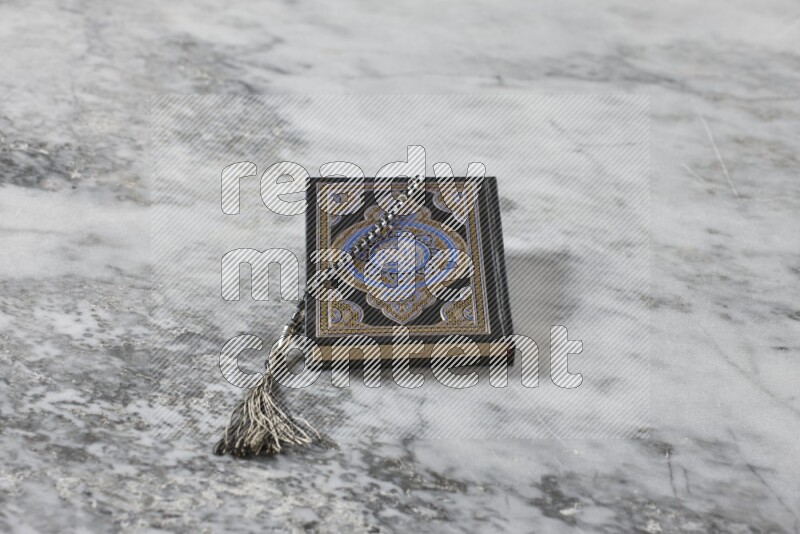 Quran with a prayer beads on grey marble background