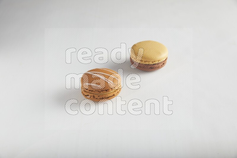 45º Shot of of two assorted Brown Irish Cream, and Yellow, and Brown Chai Latte macarons on white background