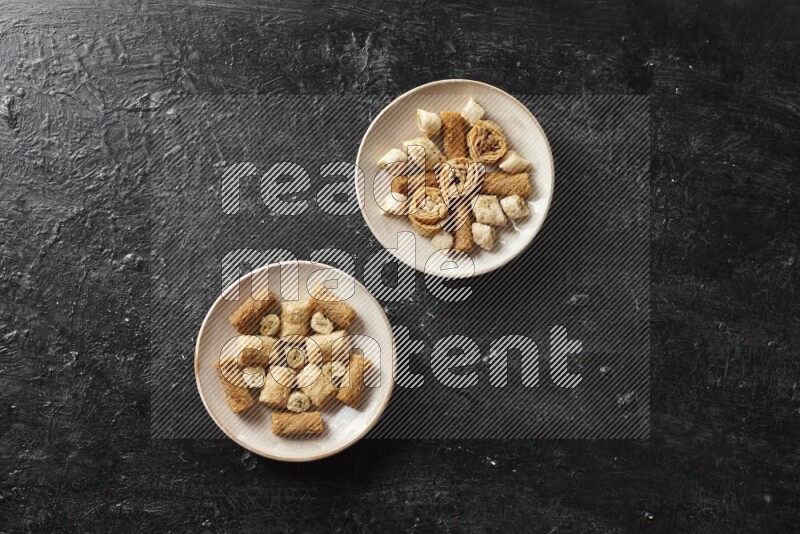 حلويات شرقية في أطباق فخارية علي خلفية سوداء خشبية