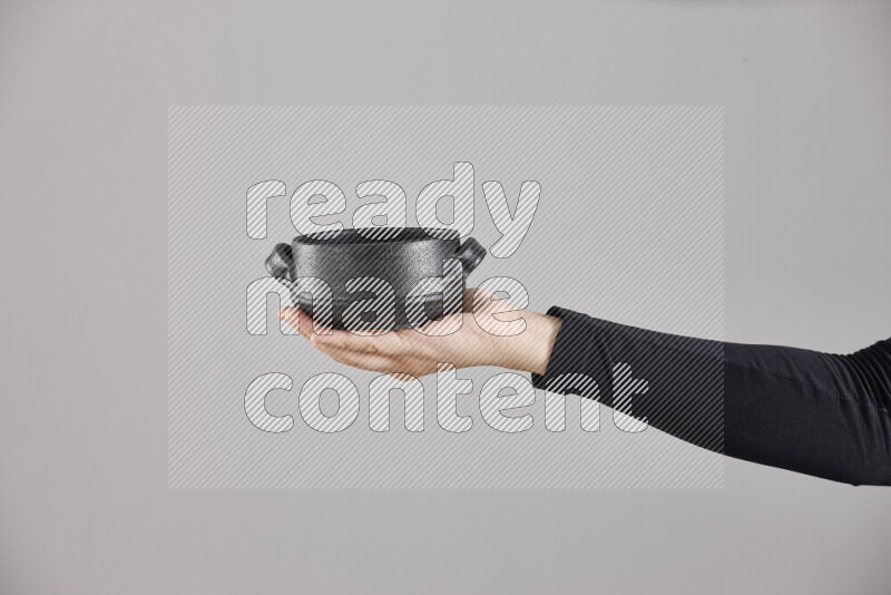 A woman in black abaya holding different pottery essentials in different positions