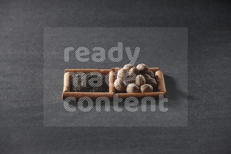 2 squares of cinnamon sticks full of tea and nutmeg on black flooring