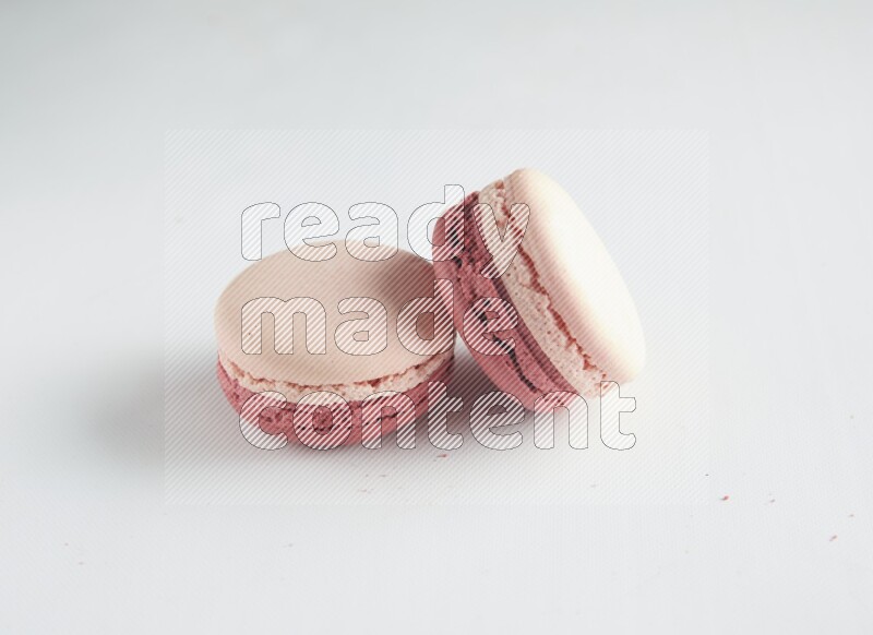 45º Shot of two Pink Litchi Raspberry macarons on white background