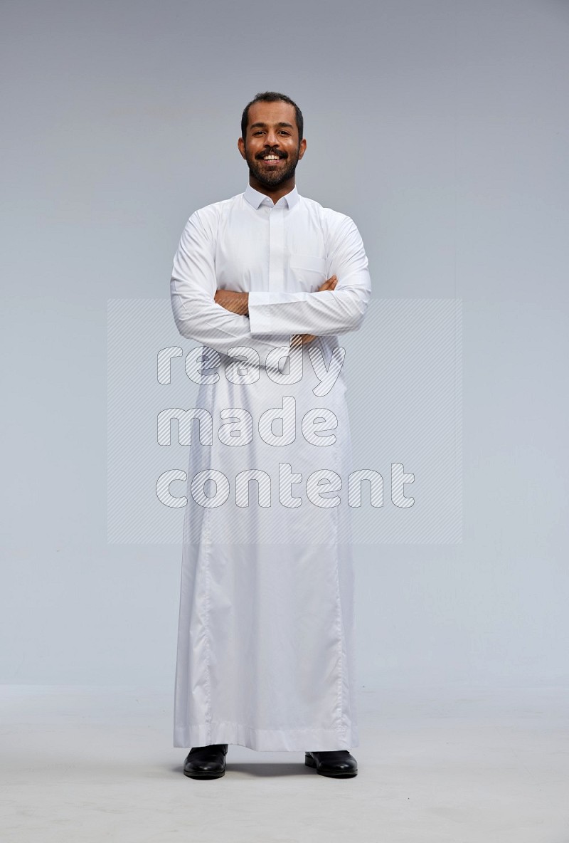 Saudi man wearing Thob standing with crossed arms on Gray background