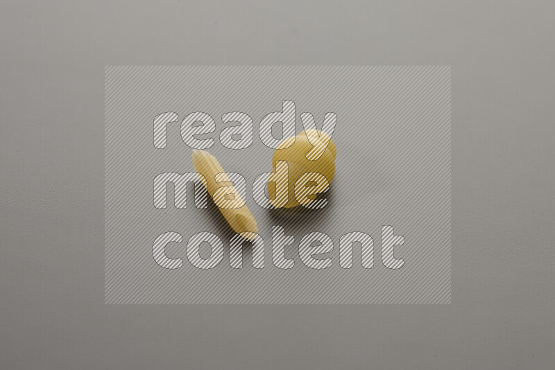 Mini penne pasta with other types of pasta on grey background