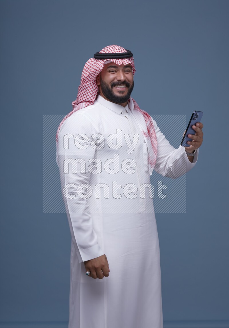A man Texting on Blue Background wearing Saudi Thob and Shomag