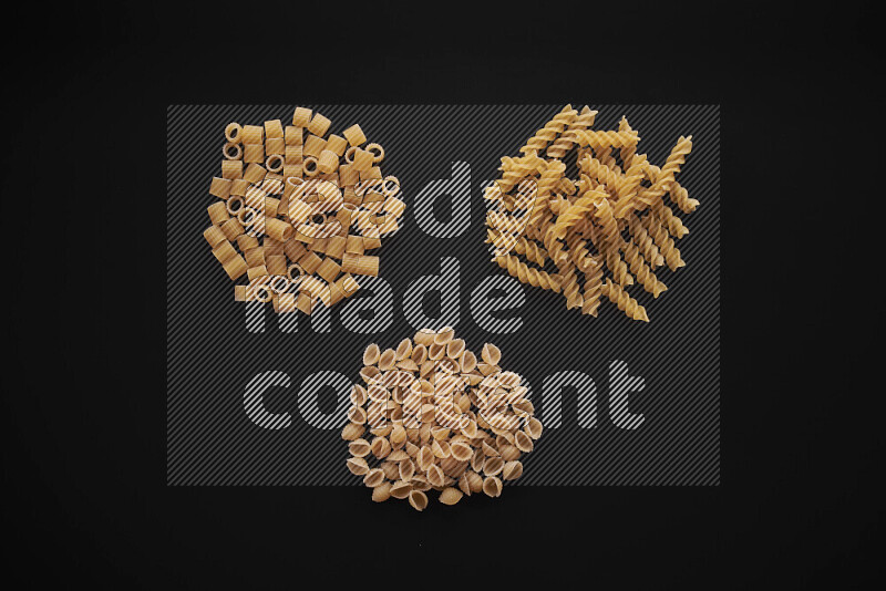 Different pasta types in bunches on black background