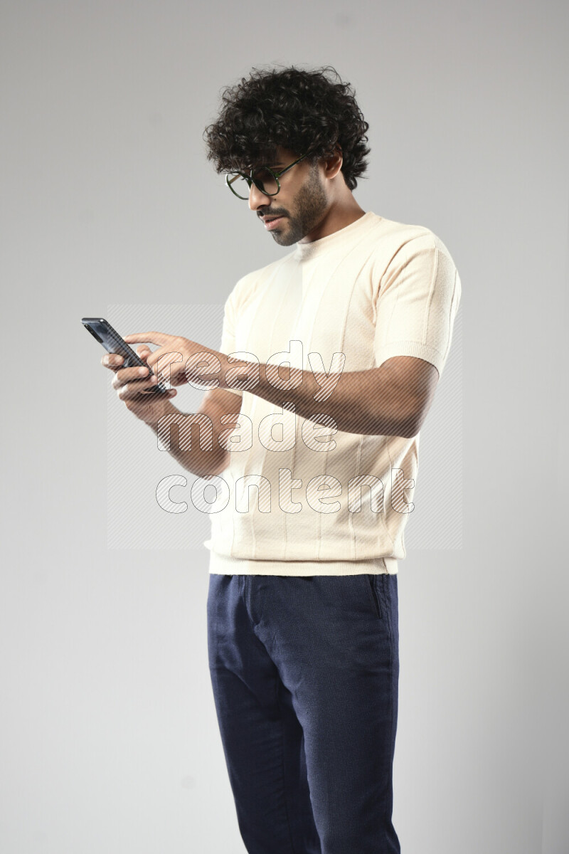 A man wearing casual standing and browsing on the phone on white background