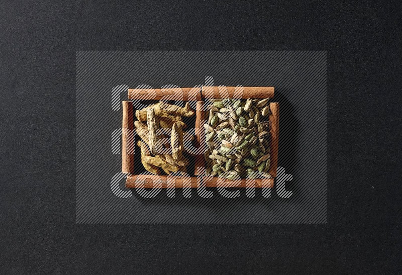 2 squares of cinnamon sticks full of cardamom and turmeric fingers on black flooring