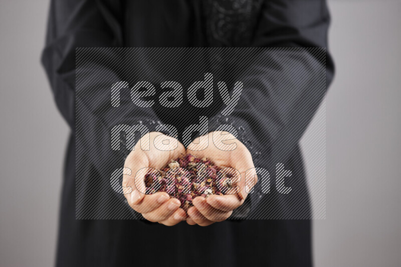 Woman in abaya holding different kinds of spices in different positions