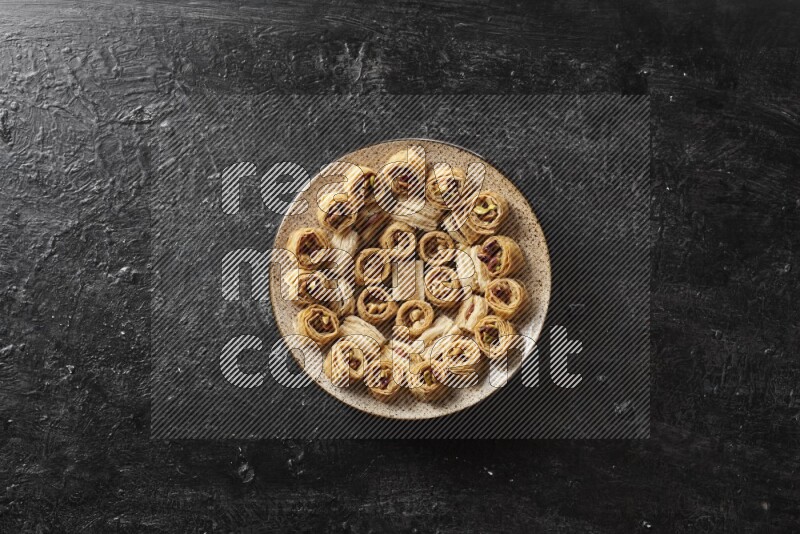 حلويات شرقية في أطباق فخارية علي خلفية سوداء خشبية