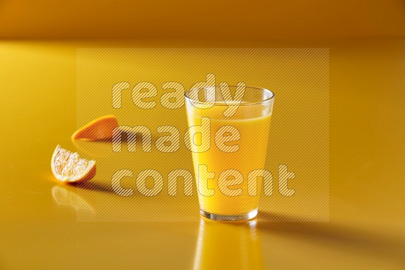 glass of orange juice on yellow background