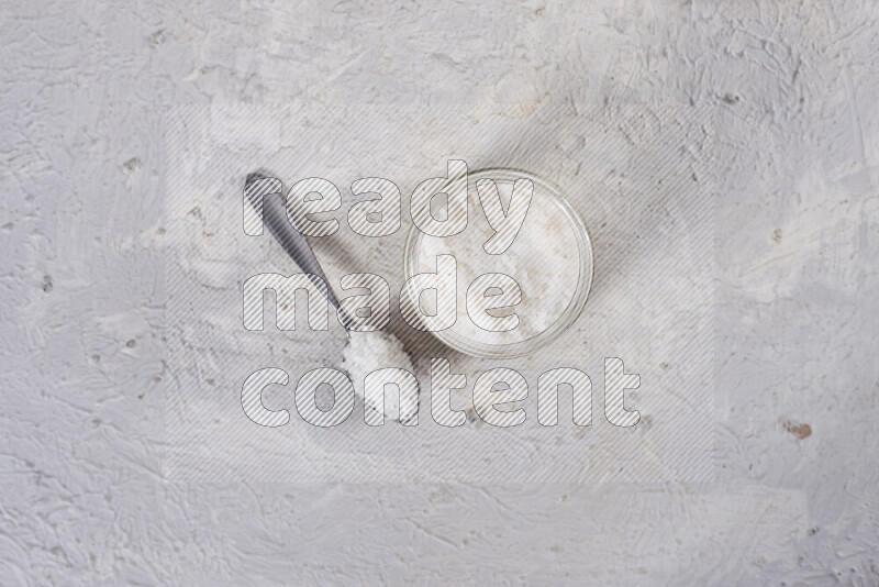 A glass jar full of coarse sea salt crystals on white background