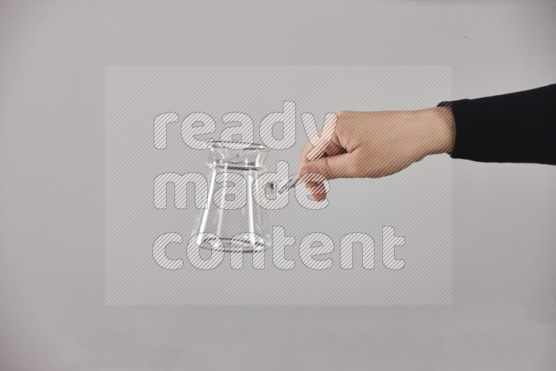 A woman in black abaya holding different glassware in different positions