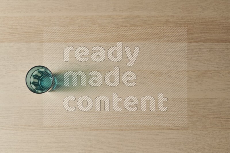 A turquoise glass cup on light wooden background