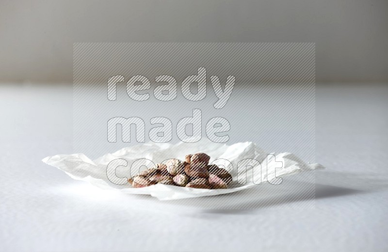 Peeled pistachios on a crumpled piece of paper on a white background in different angles