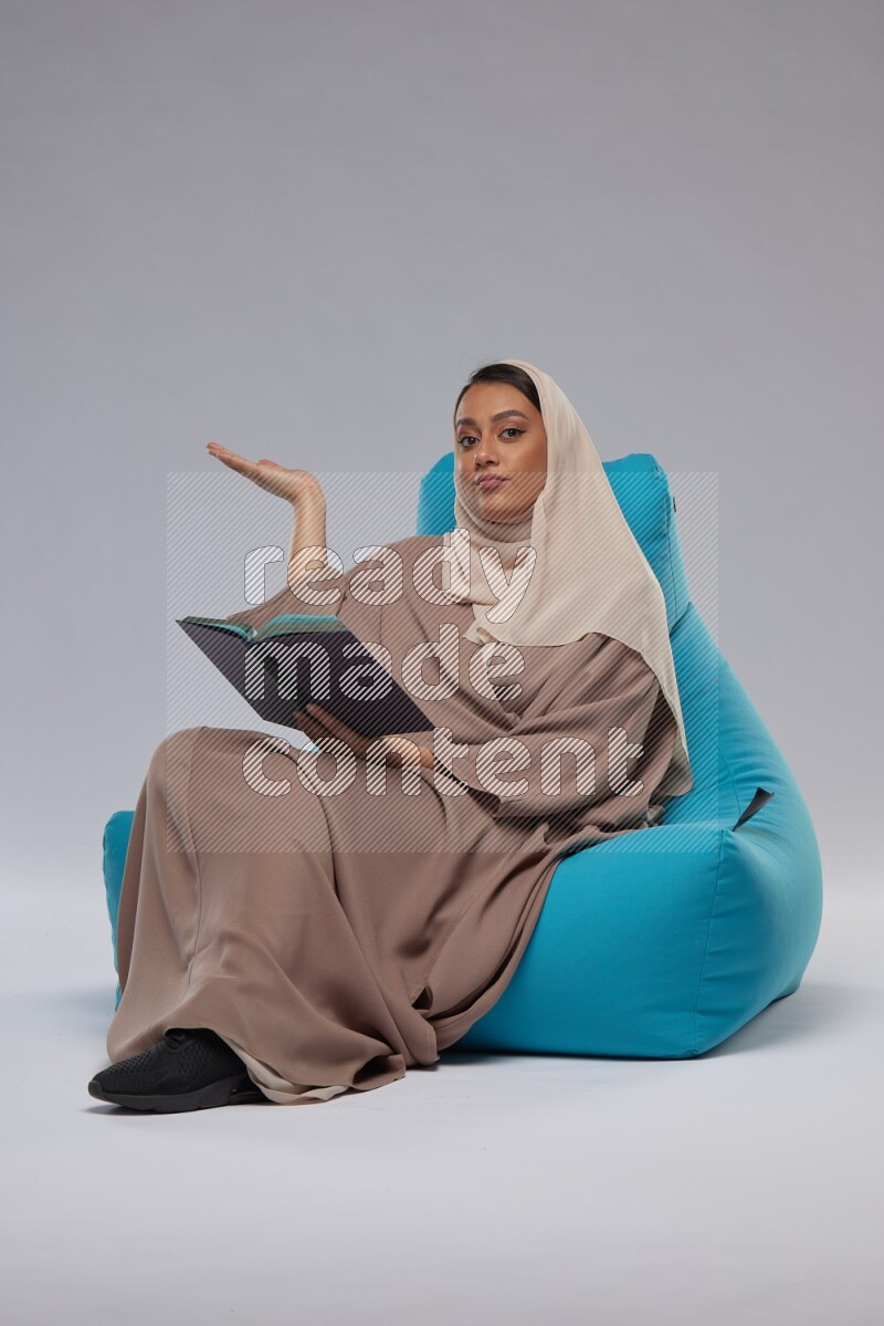 A woman sitting on a blue beanbag and reading a book