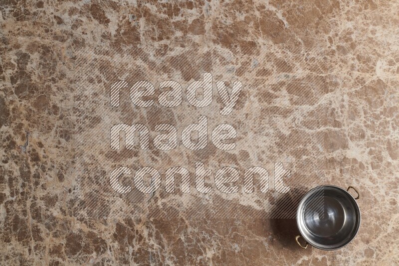 A small copper pot on beige marble background