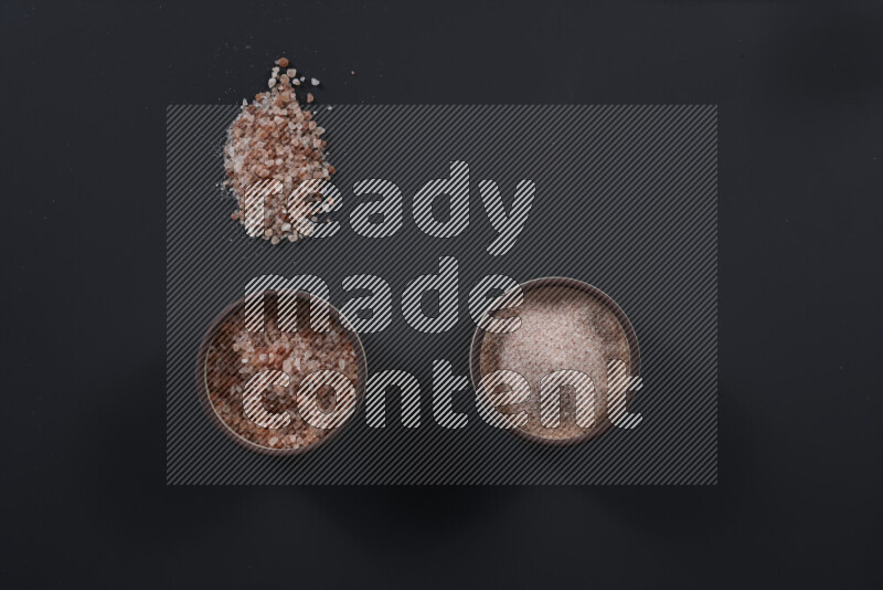 وعاء فخاري ممتلئ بملح الهيمالايا الناعم وملح الهيمالايا الخشن على خلفية سوداء