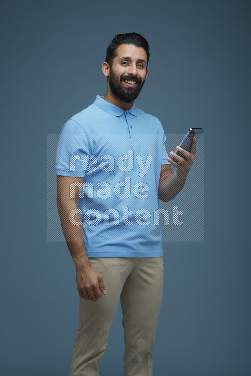 Man posing with a phone in a blue background wearing a Blue shirt