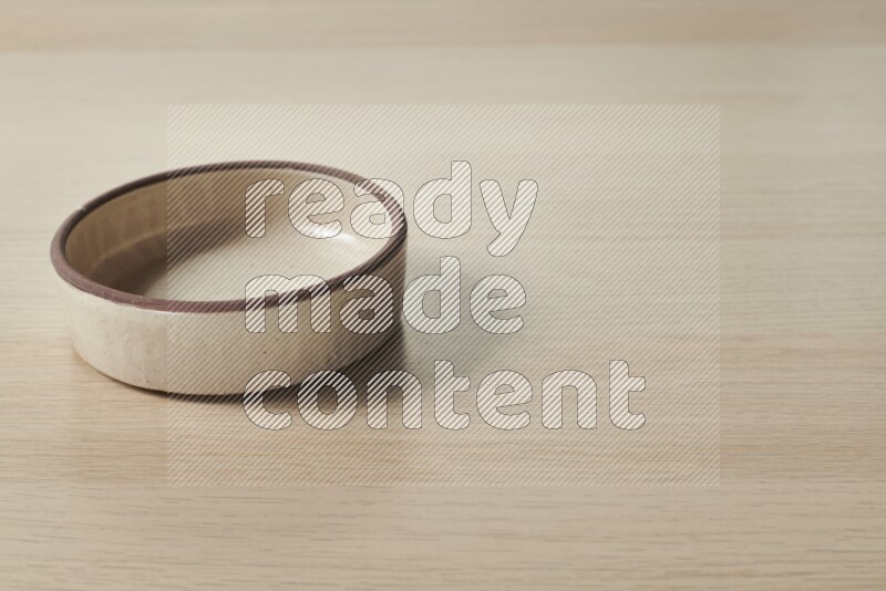 A beige pottery oven plate on light wooden background