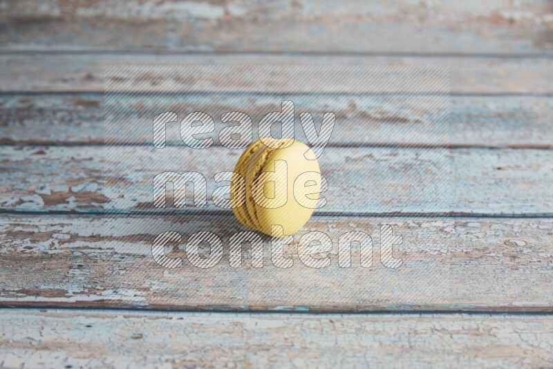 45º Shot of Yellow Lime macaron on light blue wooden background