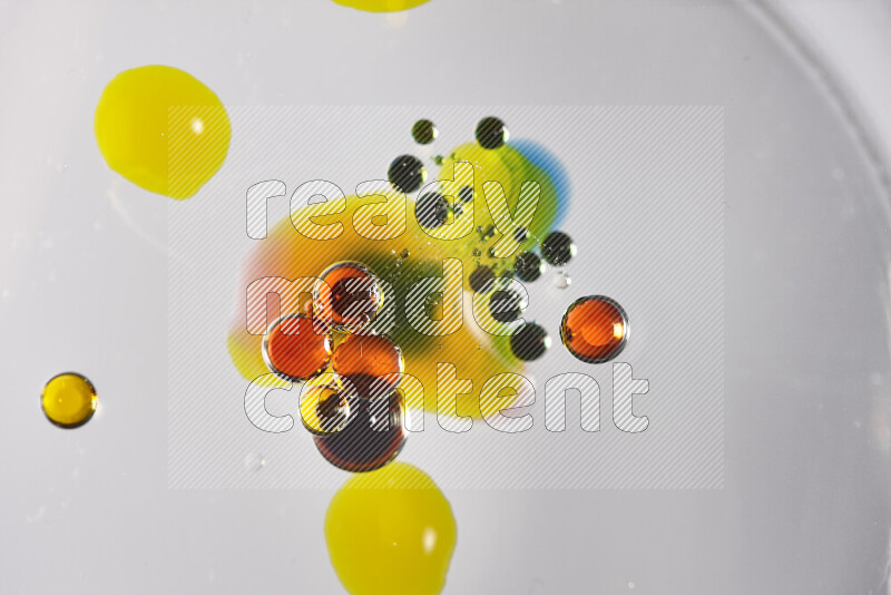 Close-ups of abstract red, blue, yellow and green watercolor drops on oil Surface on white background