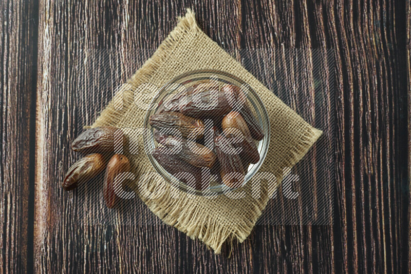 Dates in different bowls (wooden, pottery and glass) on wooden background