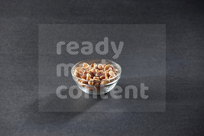 A glass bowl full of cashews on a black background in different angles