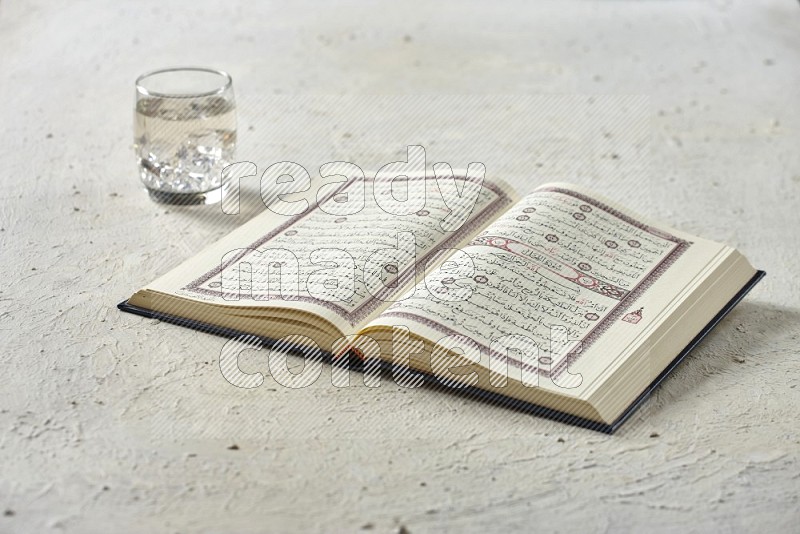 Quran with dates, prayer beads and different drinks all placed on textured white background