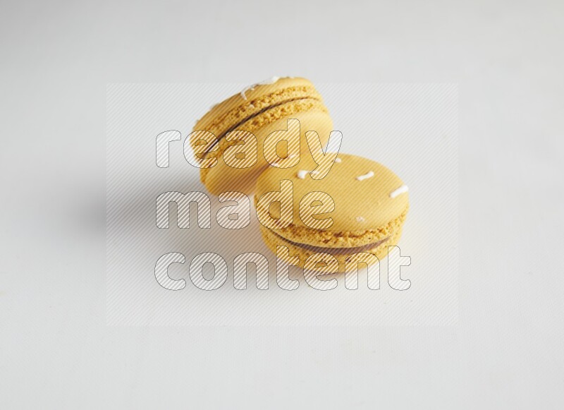 45º Shot of two Yellow Piña Colada macarons on white background