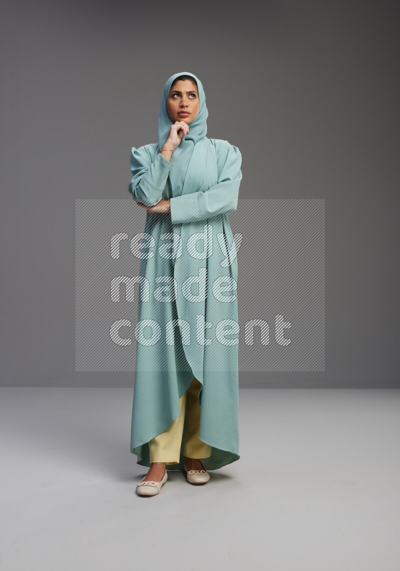 Saudi Woman wearing Abaya standing interacting with the camera on Gray background